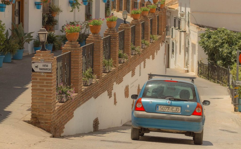 Un ancien modèle de Renault Clio roulant sur une route pittoresque, au milieu d'un paysage magnifique.
